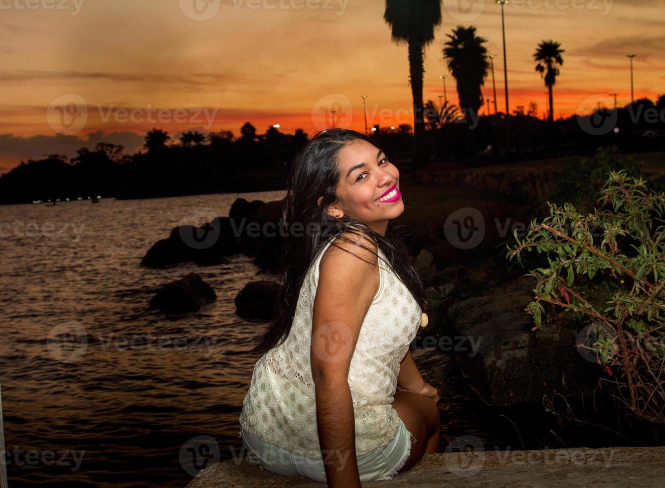 bello giovane brasiliano ragazza con un' bellissimo Sorridi a il parco a tramonto foto