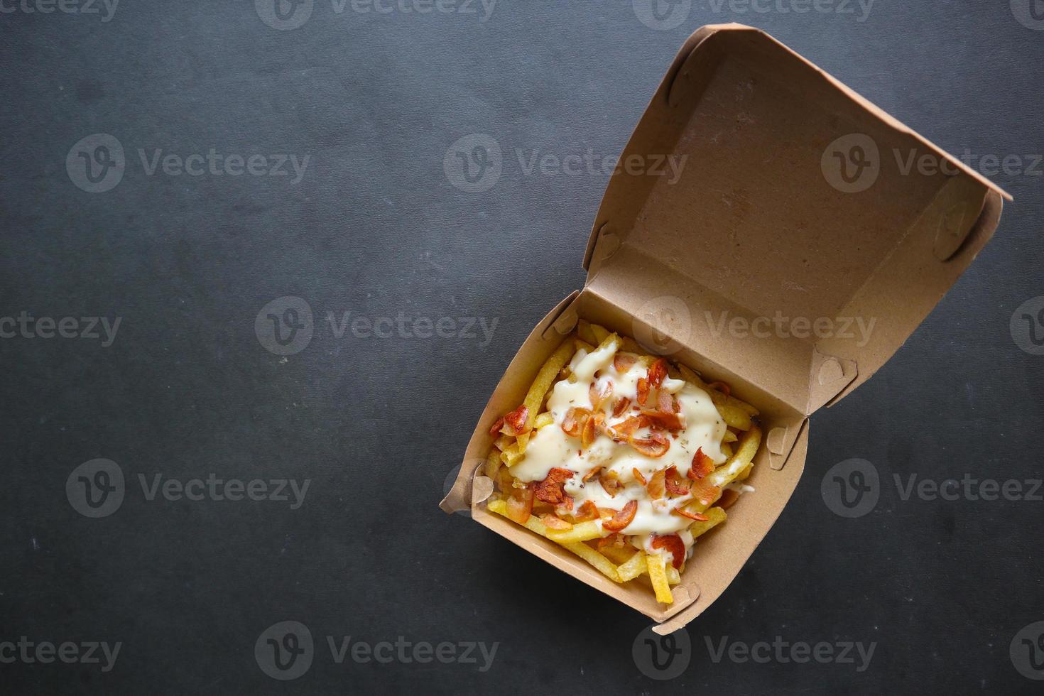 fritte patatine fritte con con fuso Cheddar formaggio o fritte formaggio con guarnizione salsiccia fette su scatola foto
