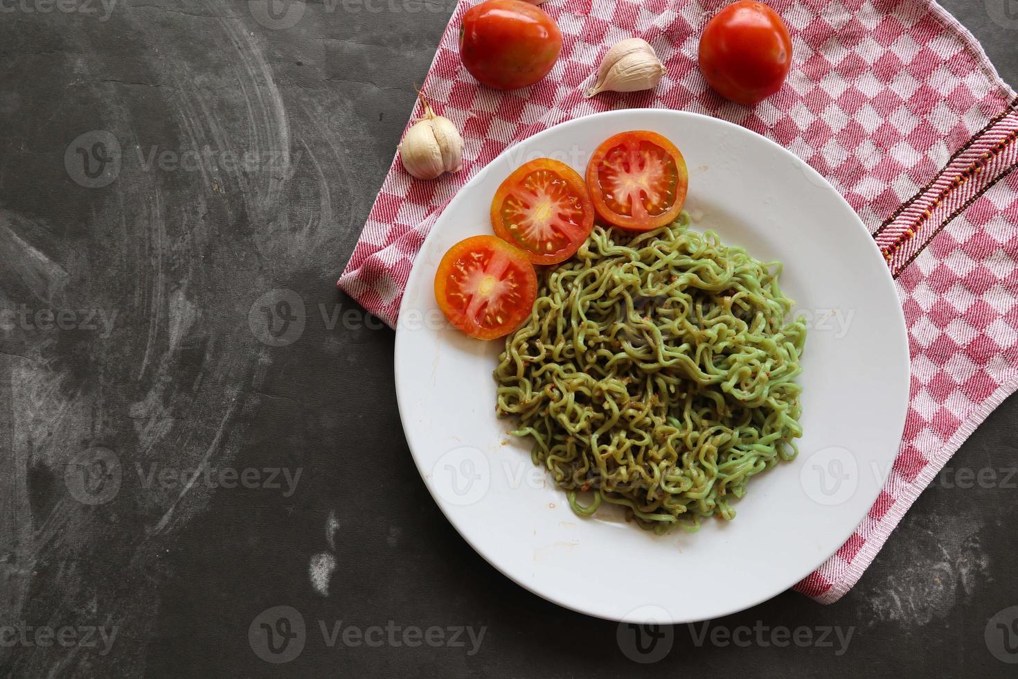 verde tagliatelle, o spinaci pasta , zucchine crudo vegano pasta immersione, e pomodori su piatto. foto