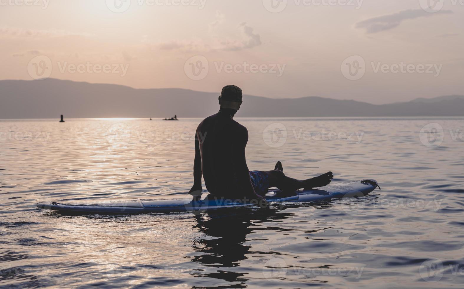 sportivo giovane uomo su cenare pagaia tavola andando per il mare a tramonto. foto