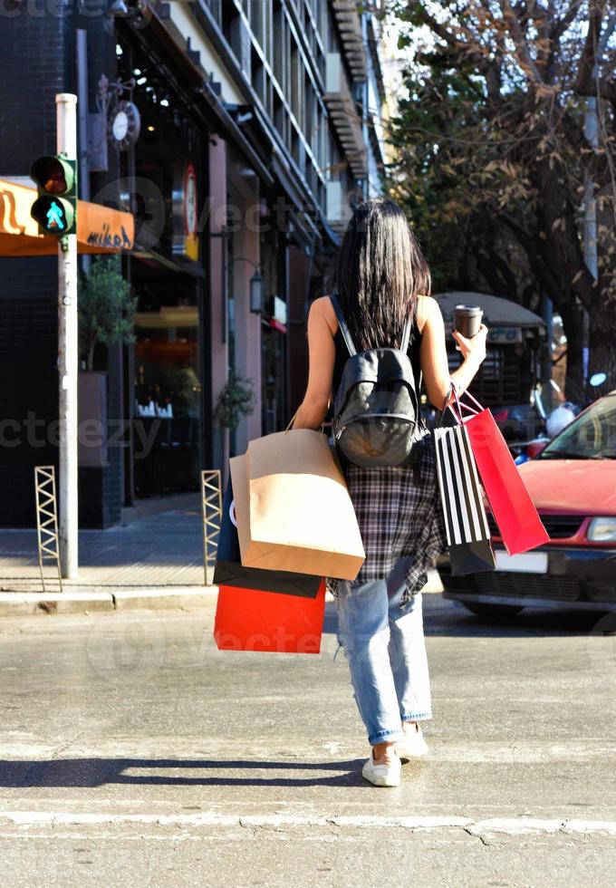 bellissimo donna a piedi su il strada con shopping borse. di moda femmina modello nel il città holdingshopping borse. foto