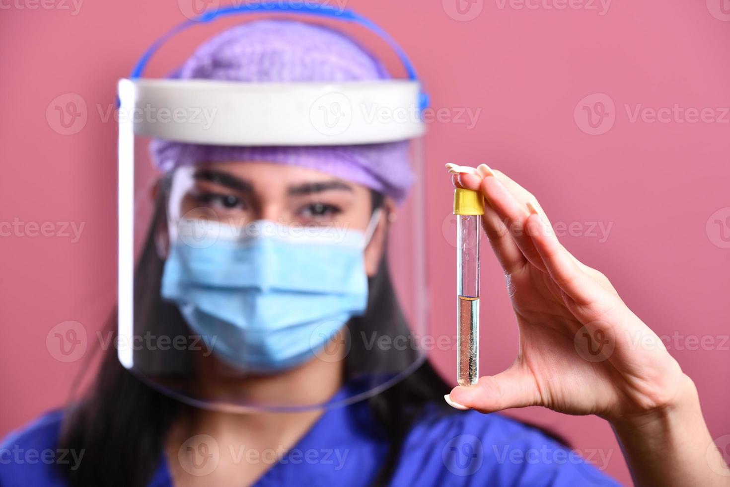 femmina medico indossare viso scudo e ppe completo da uomo per coronavirus scoppio Tenere vaccino e covid test. concetto di covid-19 foto