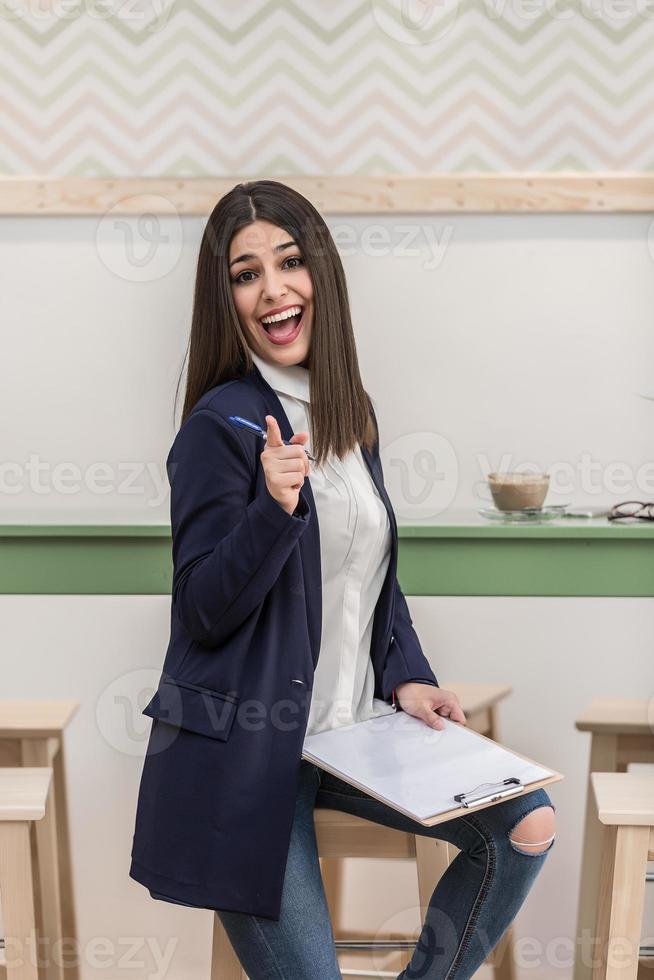 donna con appunti puntamento a telecamera nel bar foto