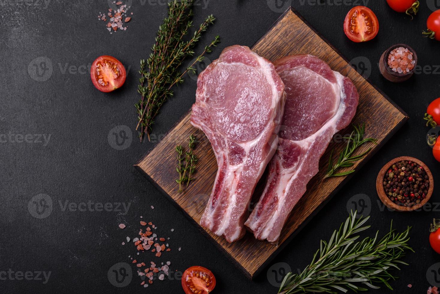 fresco crudo Maiale carne su il costolette con spezie e erbe aromatiche su un' di legno taglio tavola foto