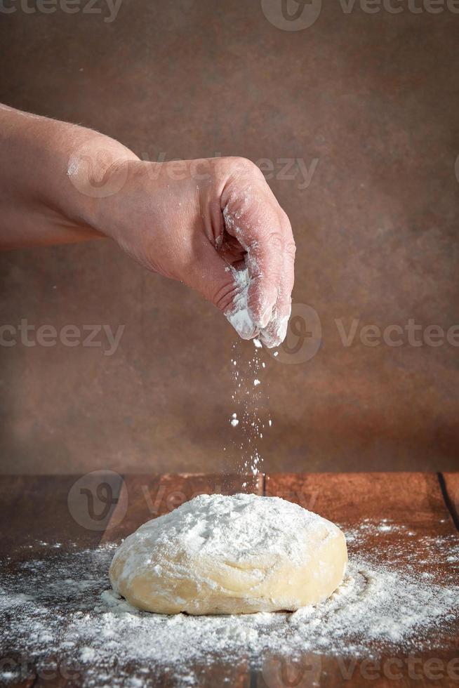 il mani di un anziano, paffuto donna siamo impasto Impasto su un' di legno tavolo. preparazione di Impasto per un' festivo torta, Pizza foto