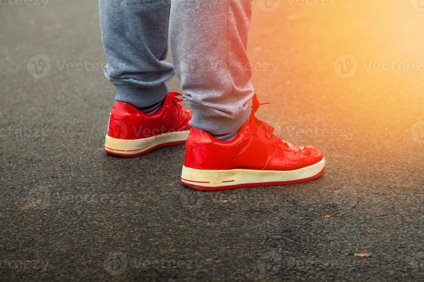 rosso scarpe da ginnastica siamo asfalto con luce del sole nel il telaio foto