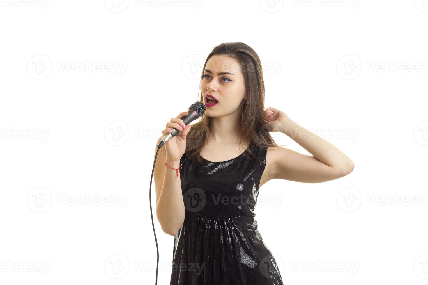 bello giovane donna nel nero vestito cantando canzone con karaoke foto