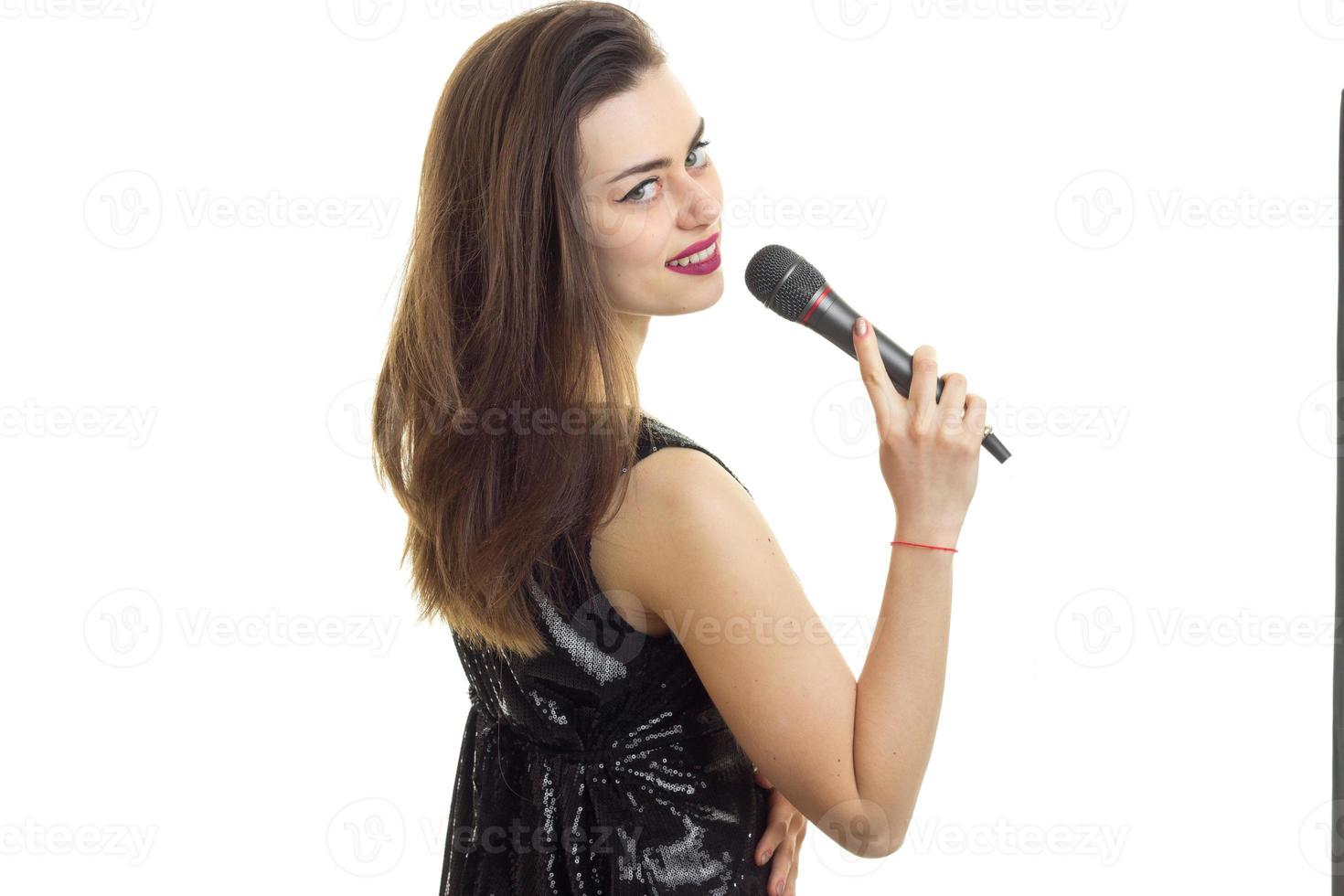carino giovane donna nel nero vestito con microfono foto