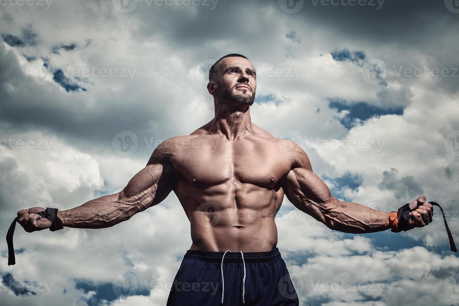 muscolare barbuto uomo in posa contro nuvoloso cielo foto