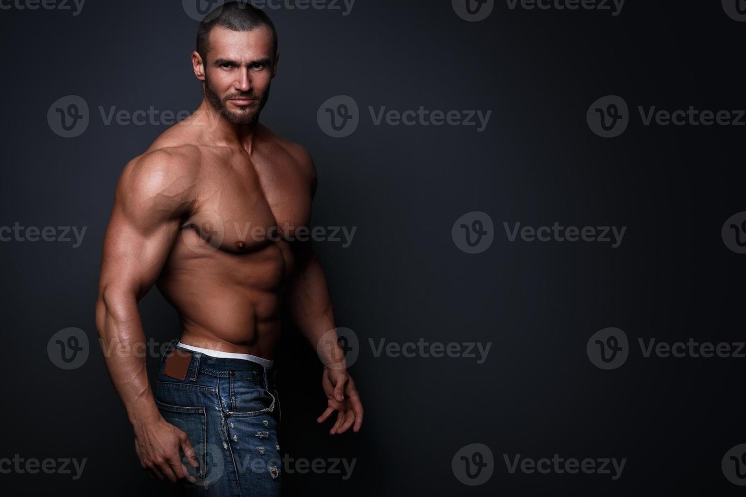 bello muscolare uomo indossare jeans in posa nel studio foto