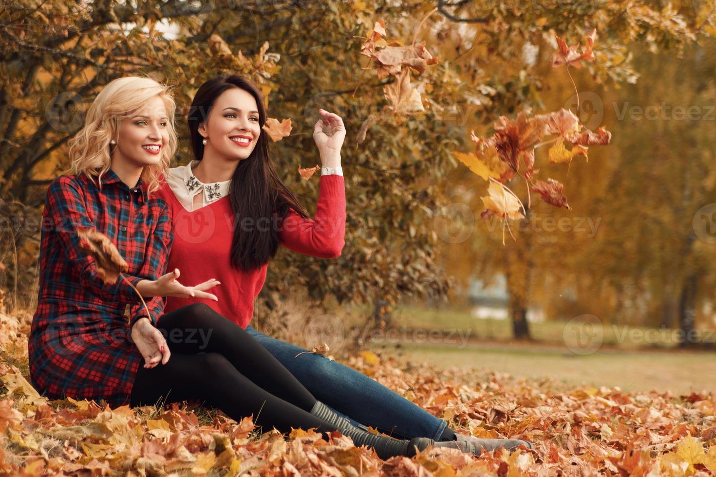 Due bellissimo ragazze amici avendo divertimento nel autunno parco foto