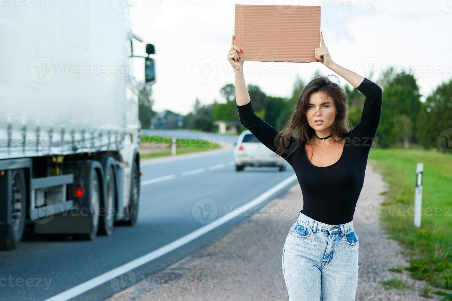 autostoppista su il strada è Tenere un' vuoto cartone cartello foto