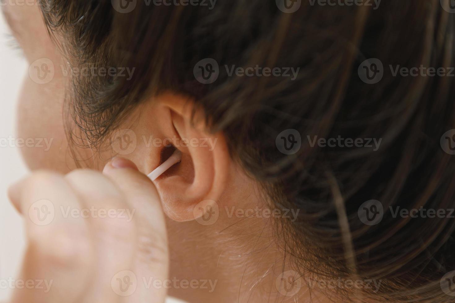 donna pulizia orecchio con un' cotone tampone foto