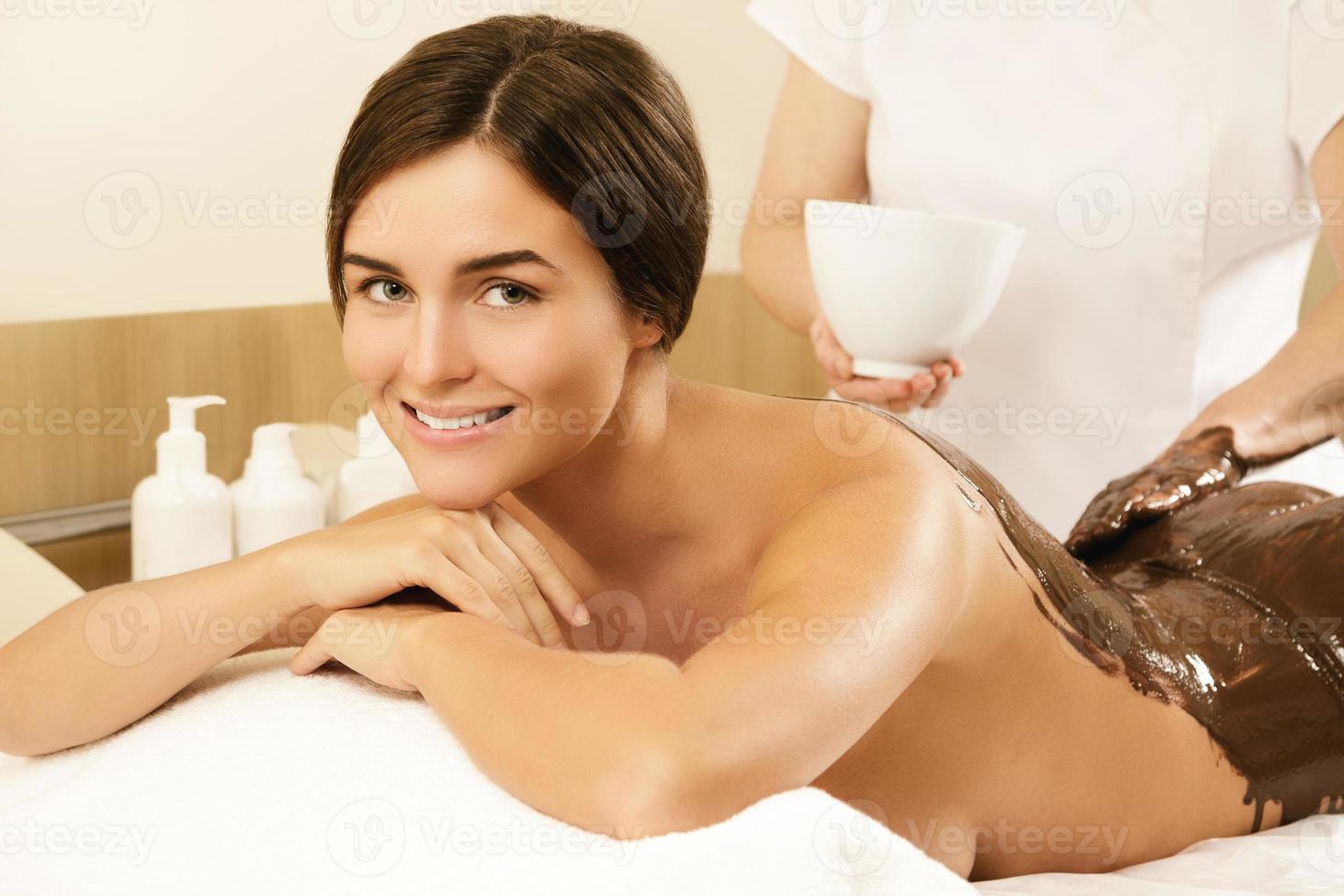 contento giovane donna durante un' cioccolato avvolgere o massaggio foto