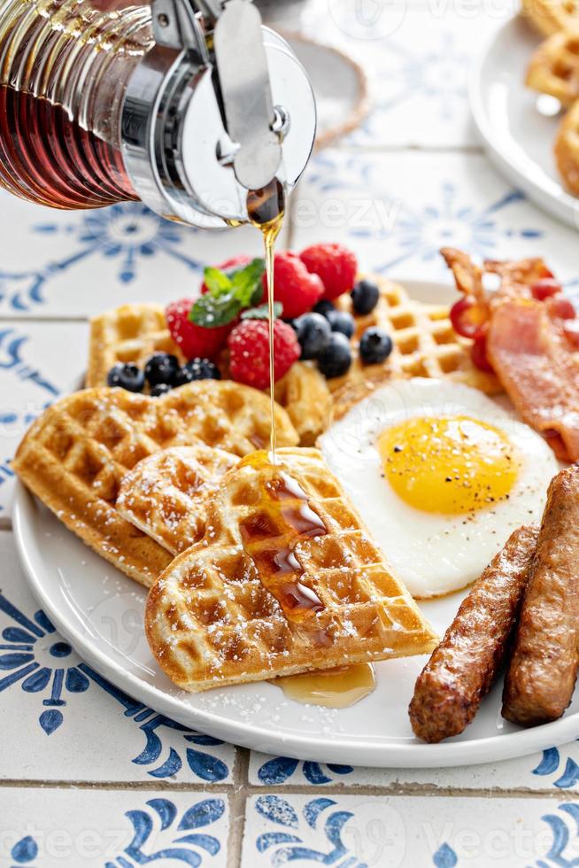 prima colazione tavolo con cialde. fritte uovo, Bacon e salsiccia foto