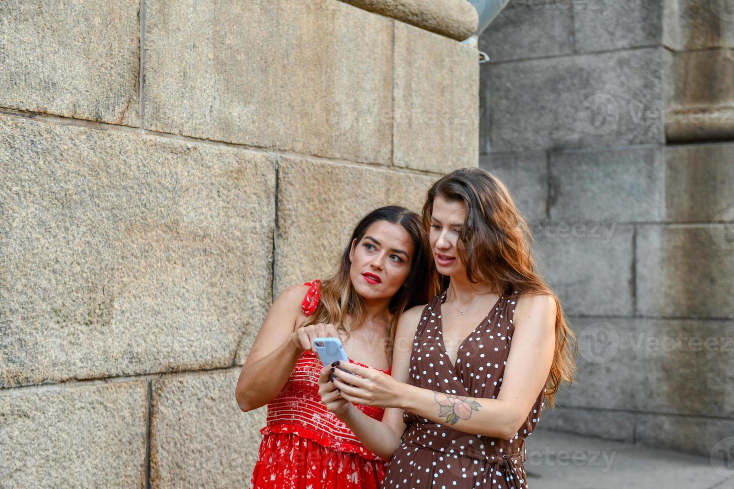 Due perso ragazze interagendo con un' mobile Telefono per ottenere indicazioni nel nuovo York città foto