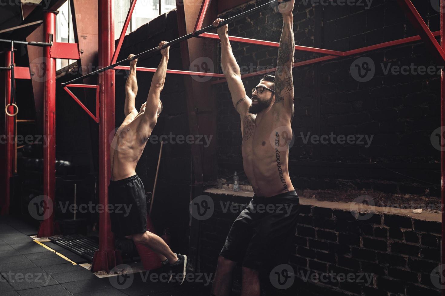 Due forte uomini fare esercizio su barre nel il Palestra foto