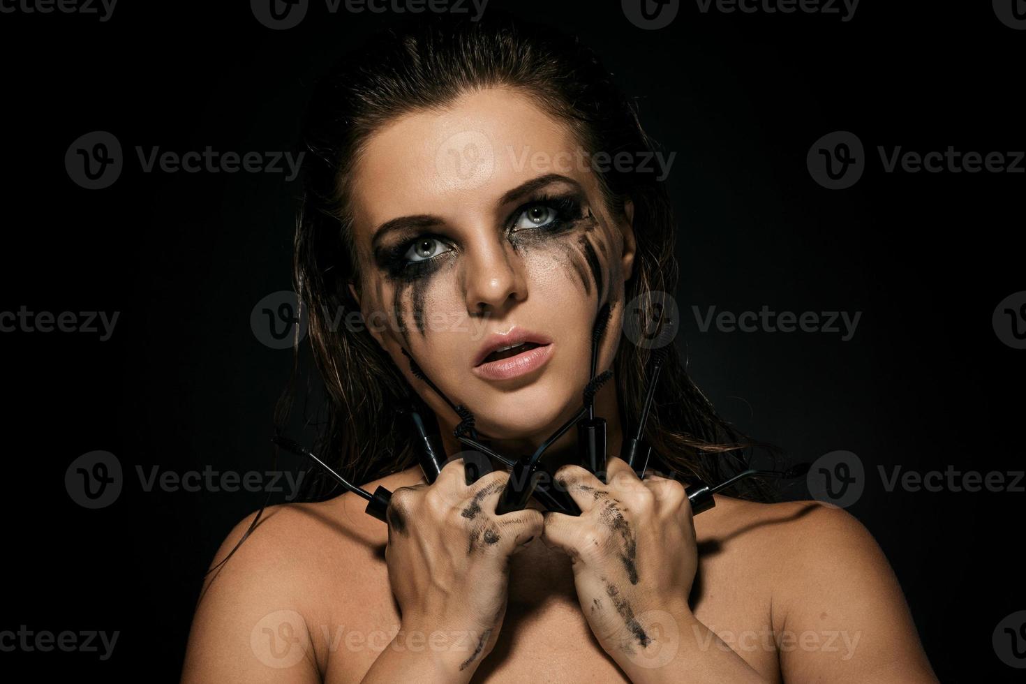 donna con macchie di trucco su sua viso e rotto mascara spazzole foto