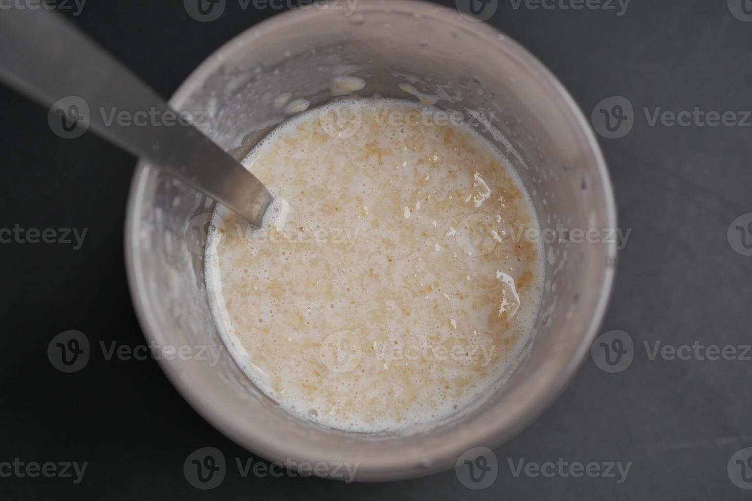 avena, banana e latte in una ciotola su sfondo nero foto