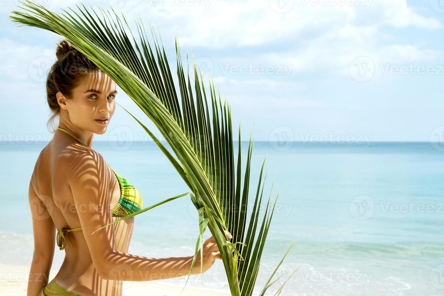 bellissimo donna con un' palma foglia su il spiaggia foto