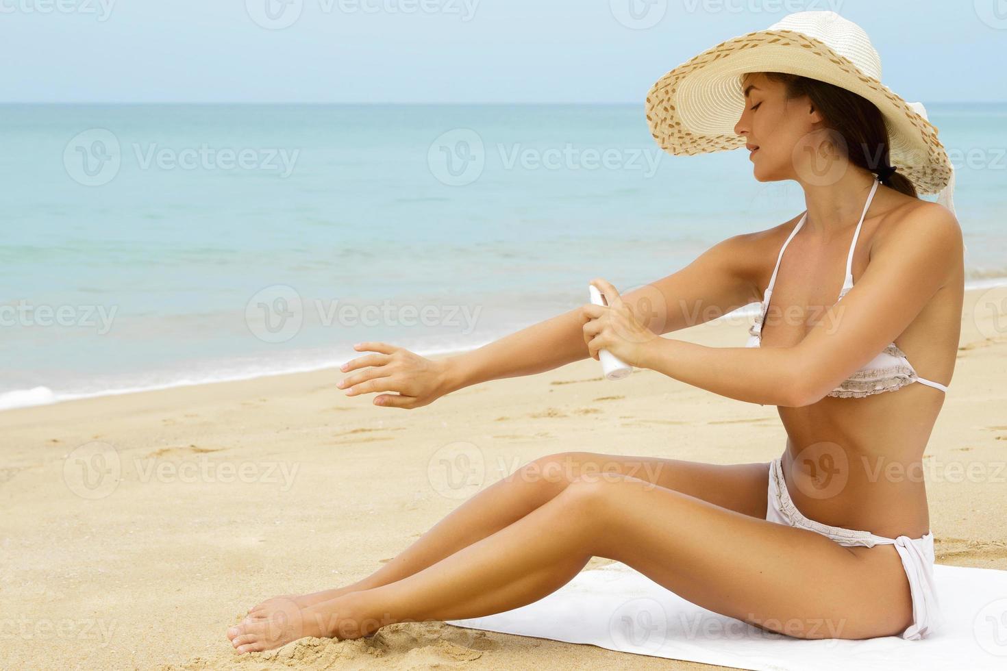 donna l'applicazione crema solare spray su sua corpo foto