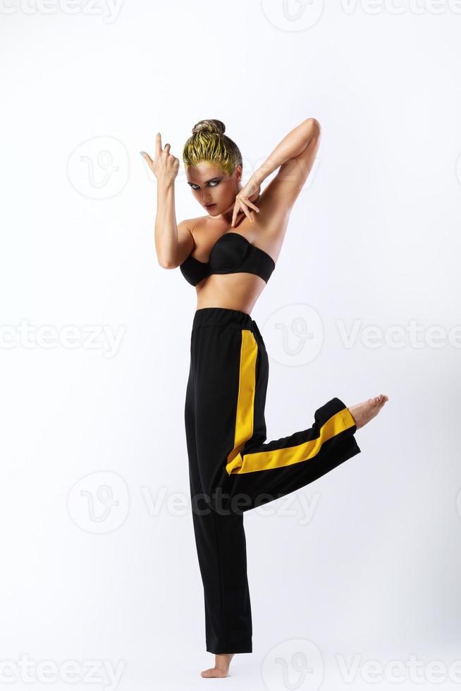 elegante donna con giallo capelli e pantaloni da ginnastica su grigio sfondo foto