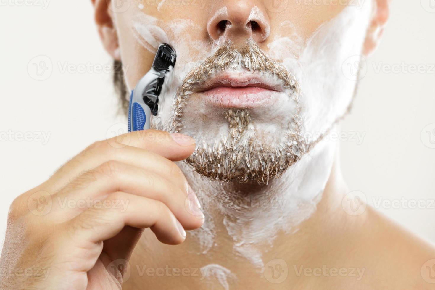 uomo con un' sicurezza rasoio e rasatura crema su il suo viso foto