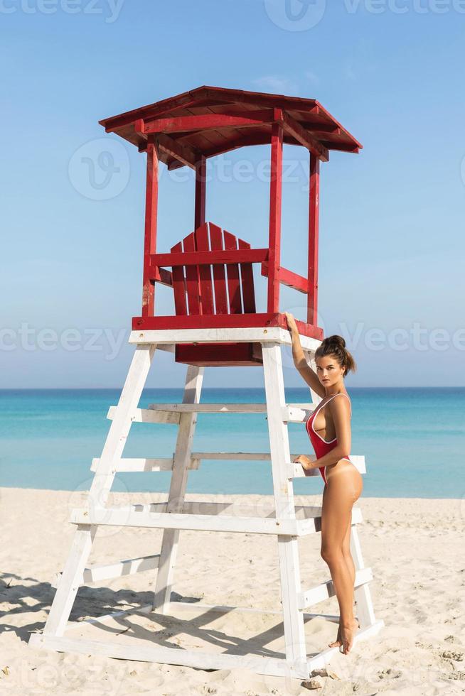 sexy donna nel rosso costume da bagno in posa accanto un' Bagnino Torre foto