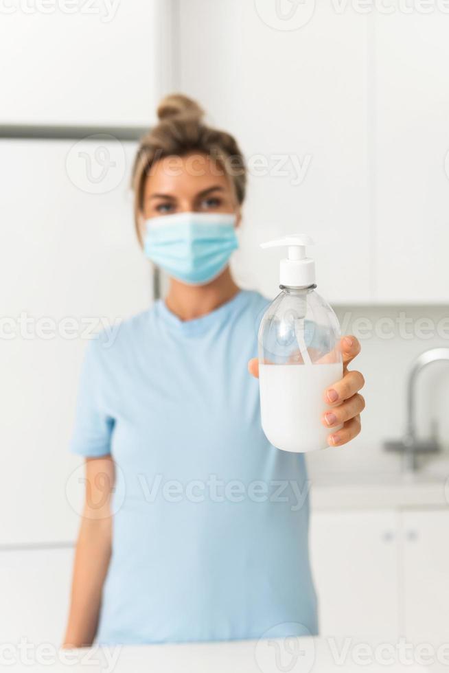 donna utilizzando mano disinfettante o liquido sapone per mani disinfezione a casa foto