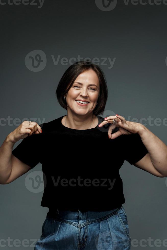 positivo mezzo anziano donna indossare nero maglietta con vuoto spazio foto