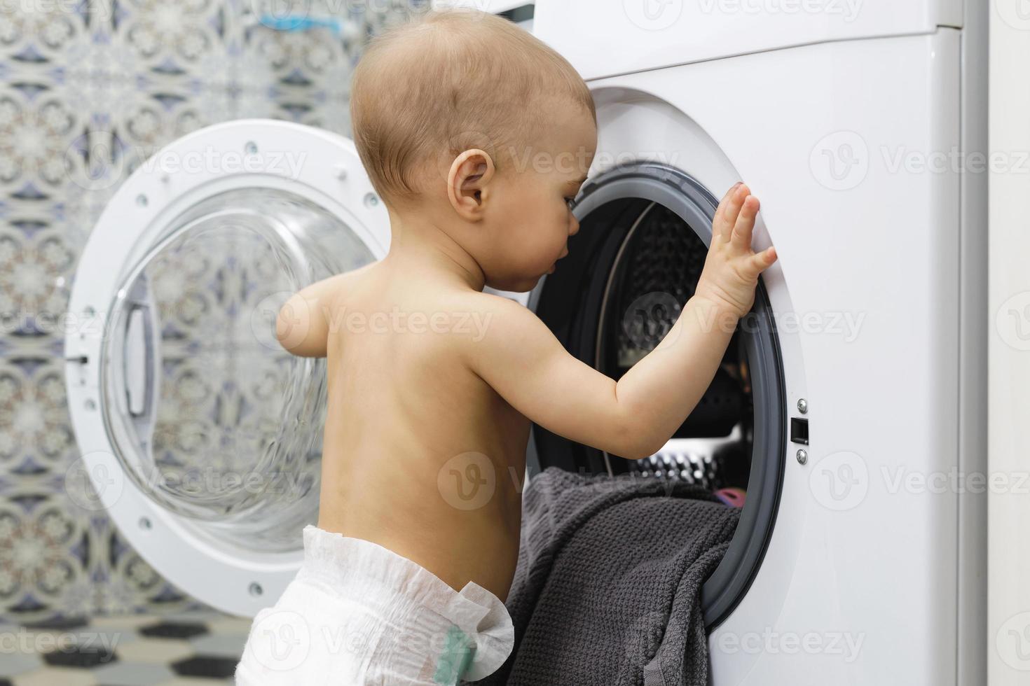 carino bambino ragazzo è guardare dentro il lavaggio macchina foto