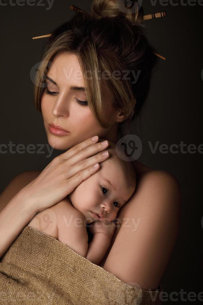 bellissimo madre e sua poco bambino siamo avvolto nel tela di sacco foto