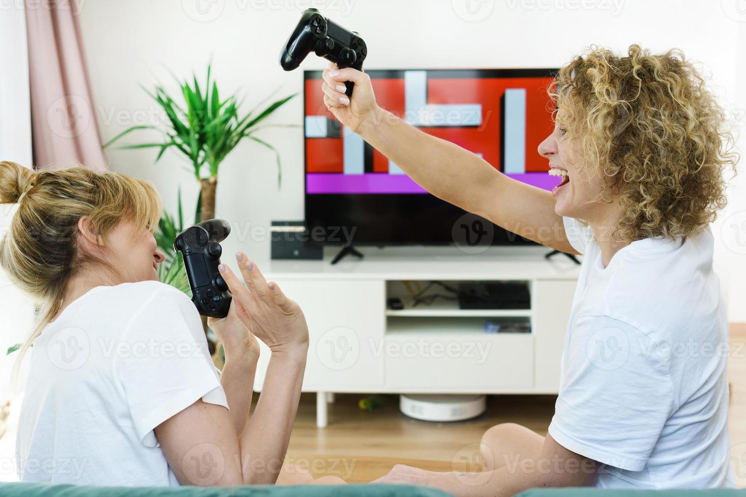 Due bellissimo ragazze giocando video gioco consolle nel un' vivente camera foto