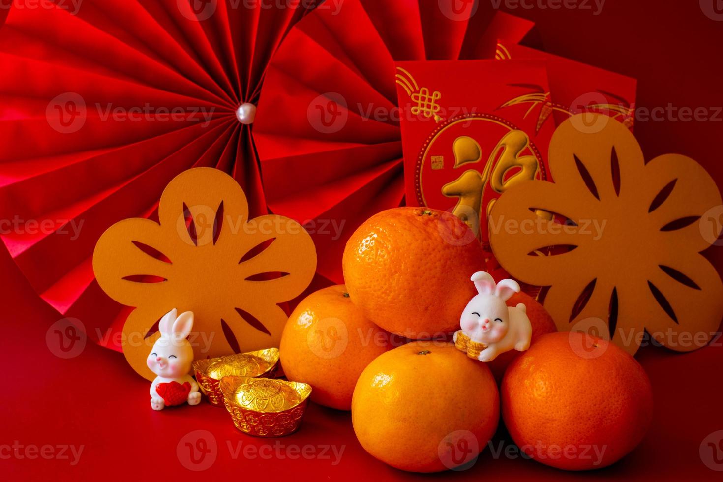 Cinese nuovo anno di il coniglio Festival concetto. mandarino arancia, rosso buste, coniglio e oro lingotto con rosso carta fan. tradizionale vacanza lunare nuovo anno. Cinese personaggio cai senso i soldi. foto