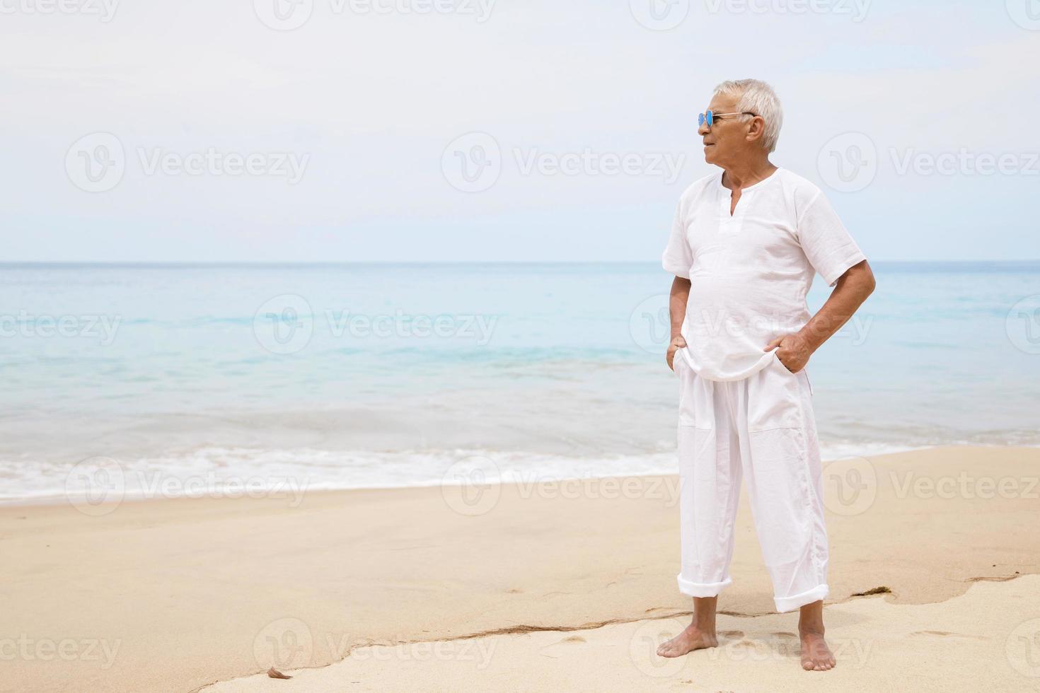 contento anziano uomo a piedi su il spiaggia foto