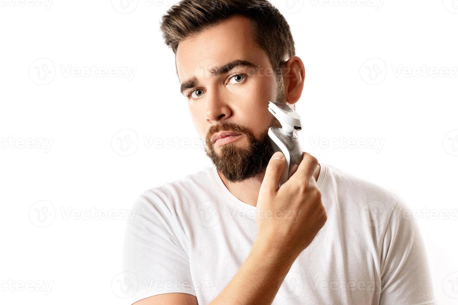bello barbuto uomo è utilizzando elettrico trimmer foto