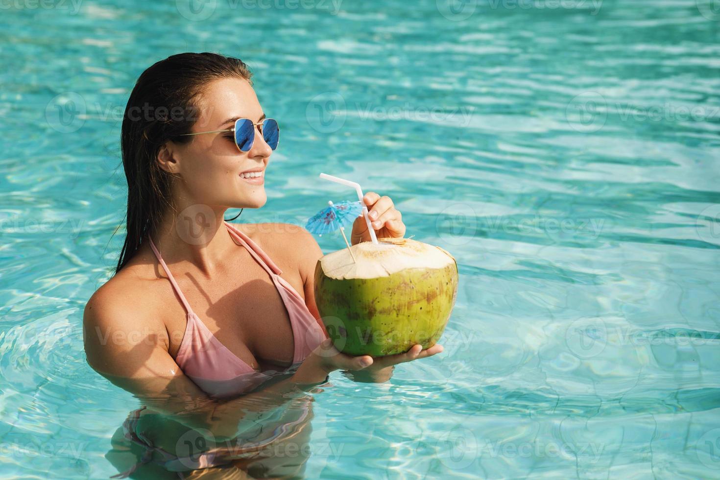 donna rilassante nel il nuoto piscina e potabile Noce di cocco acqua foto