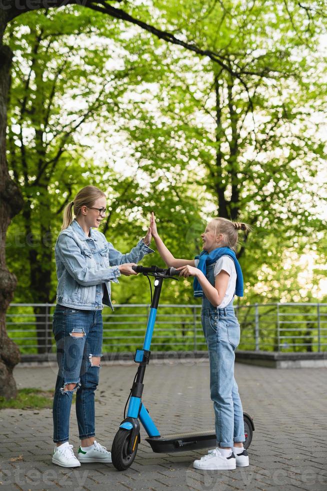 madre e figlia fabbricazione alto cinque gesto prima equitazione elettrico scooter foto