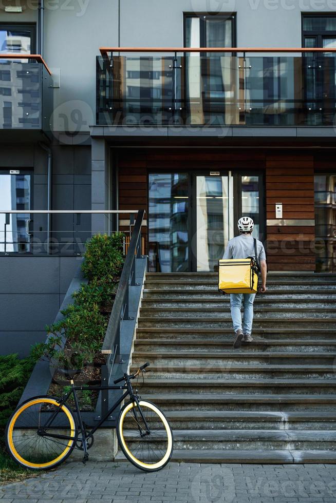 esprimere consegna Corriere con isolato Borsa andando su il le scale dopo parcheggio bicicletta. foto