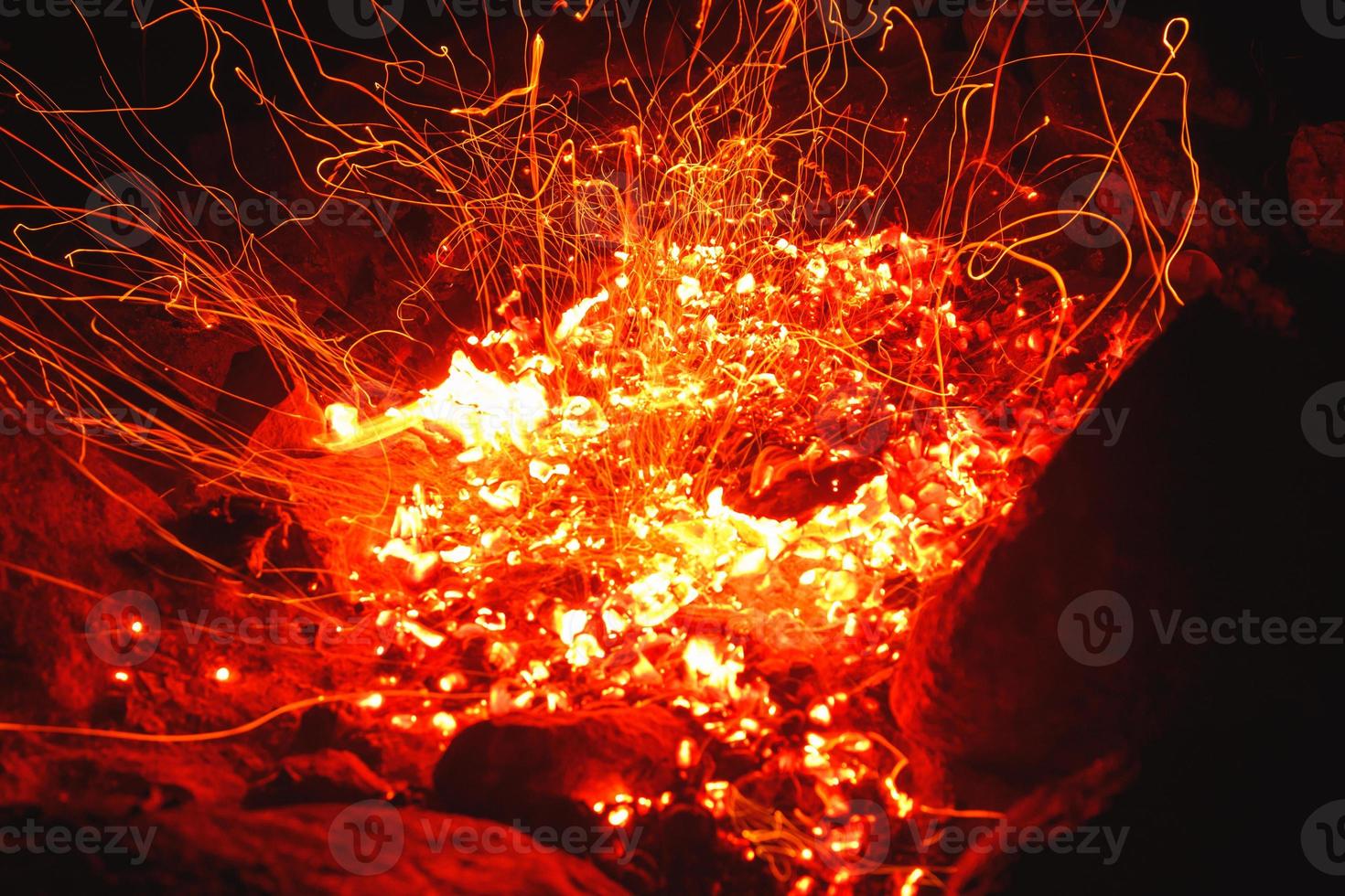 avvicinamento tiro di fuoco di bivacco brillantemente ardente a notte lancio brilla. foto