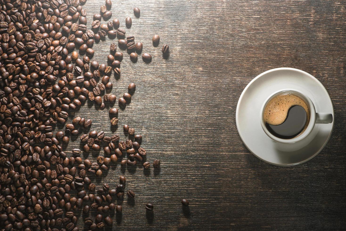 tazza di caffè con chicchi di caffè sul vecchio tavolo foto