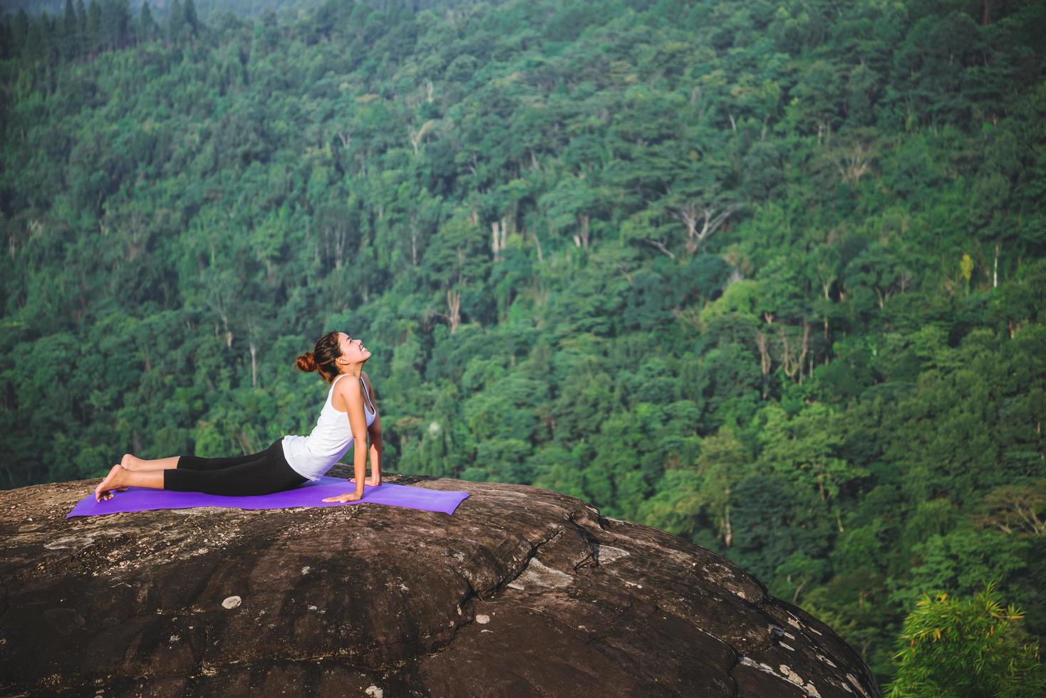 le donne asiatiche si rilassano durante le vacanze. gioca se lo yoga. sulla rupe rocciosa della montagna. natura delle foreste di montagna in thailandia. giovane donna che pratica yoga nella felicità femminile della natura. esercizio di yoga foto