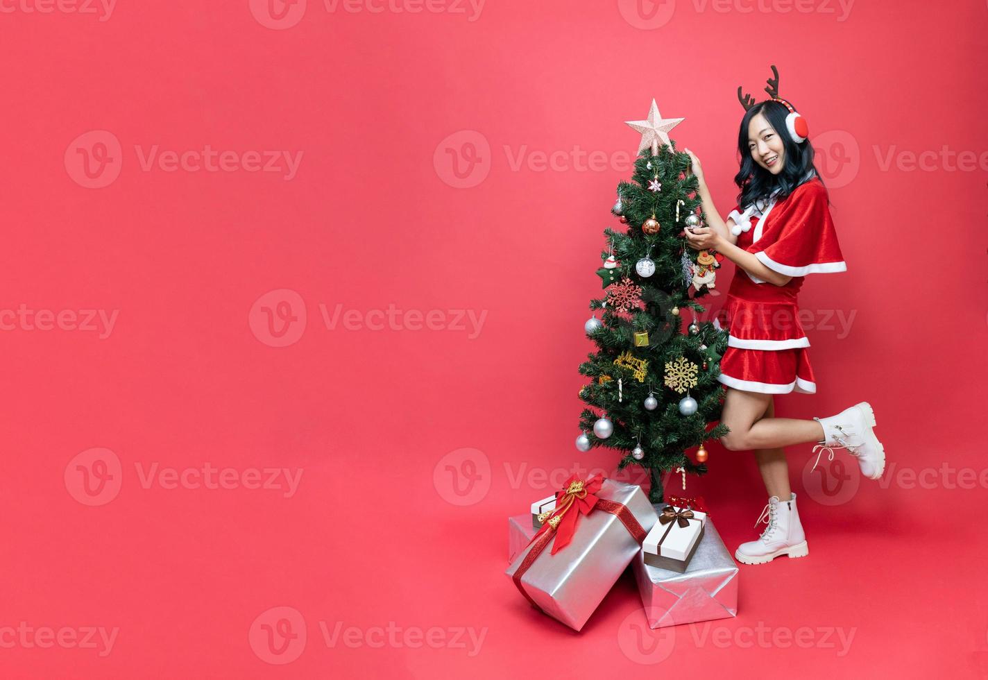 bellissimo Asia donna nel rosso santy costume decorare il Natale albero. nuovo anno celebrazione. Natale vigilia. foto