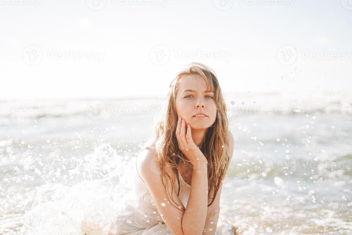 giovane bionda bellissimo donna con lungo capelli nel bianca vestito godendo vita su mare spiaggia foto