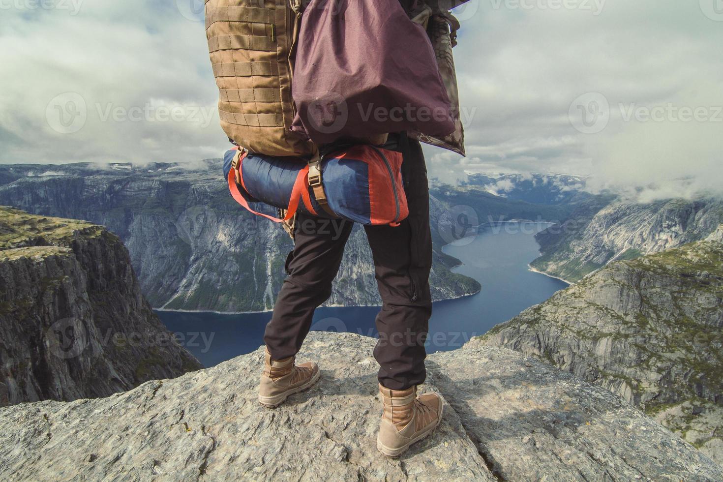 escursionista con effetti personali su roccia al di sopra di fiume panoramico fotografia foto