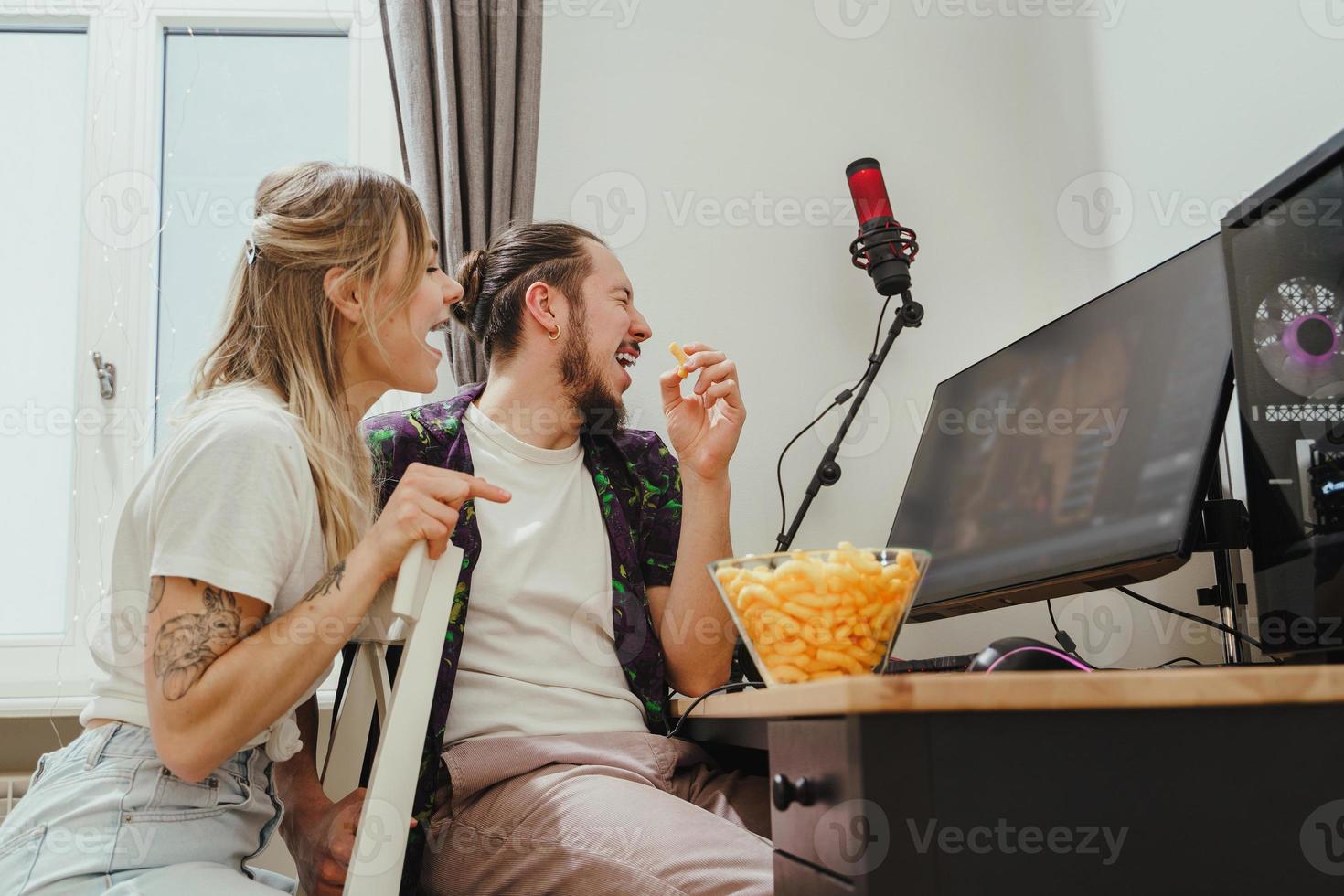 coppia mangiare formaggio sbuffi mentre giocando video Giochi o Guardando qualcosa in linea a casa foto