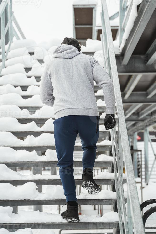 atletico uomo in esecuzione su le scale durante il suo inverno allenarsi foto