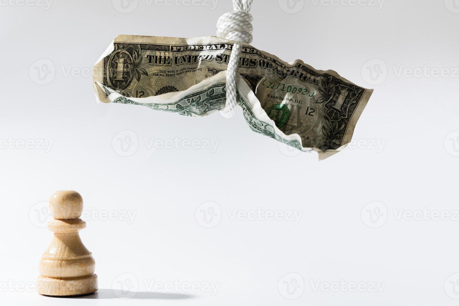 spiegazzato uno dollaro conto sospeso su un' bianca corda con di legno pezzo degli scacchi in piedi sotto. foto