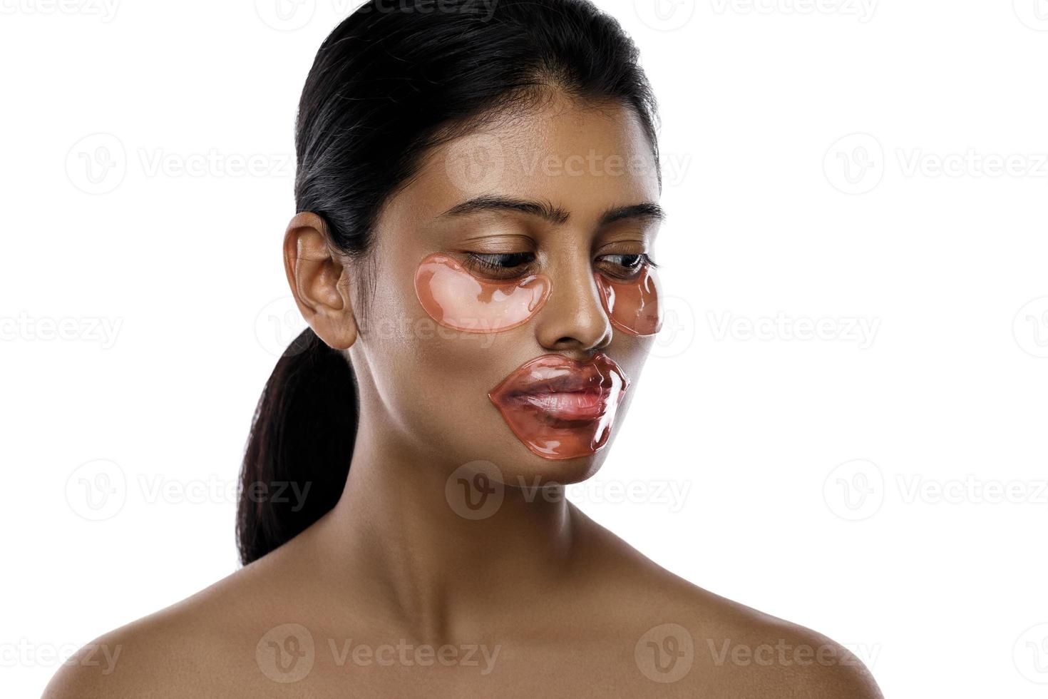 bellissimo indiano donna con idratante occhio cerotti e labbro maschera su sua viso foto
