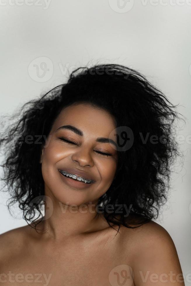 sorridente nero donna con dentale bretelle su sua denti foto